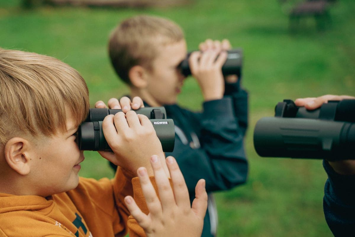 Children outdoors in daylight using binoculars