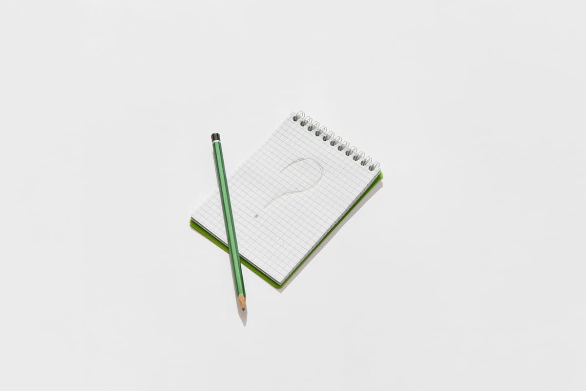 A notepad and pencil beside a drawn question mark