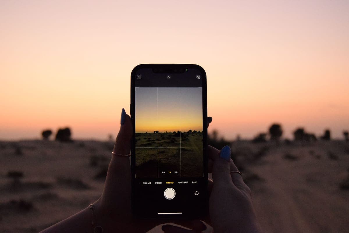 Hands holding a smartphone photographing a landscape at dusk