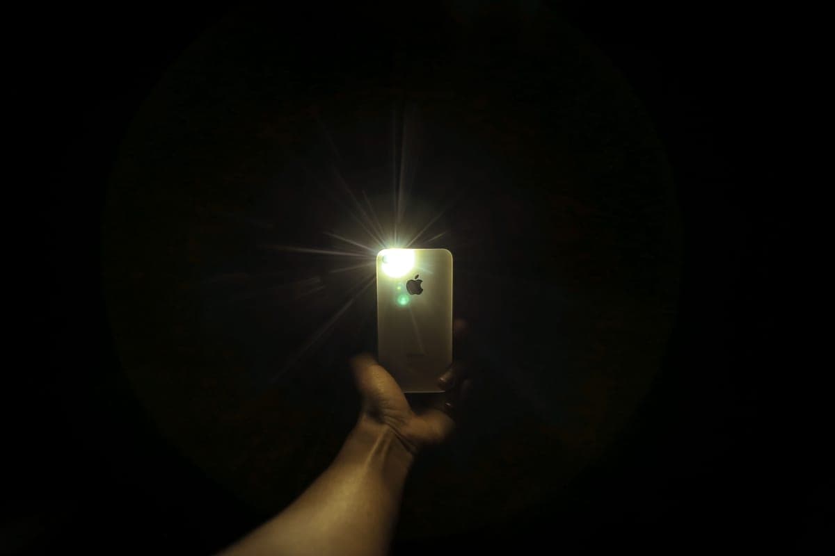 A glowing phone screen held up outdoors in the dark