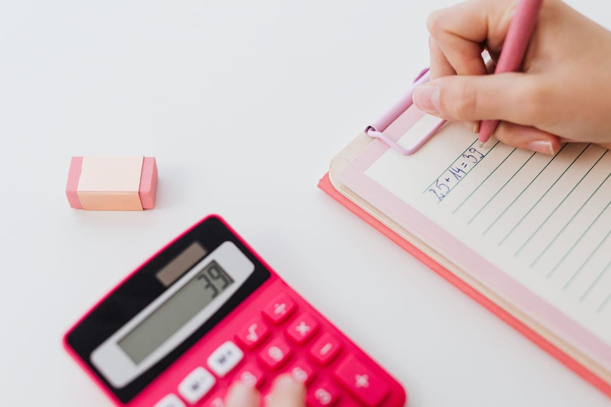 Hands working through calculations with a calculator and a notebook