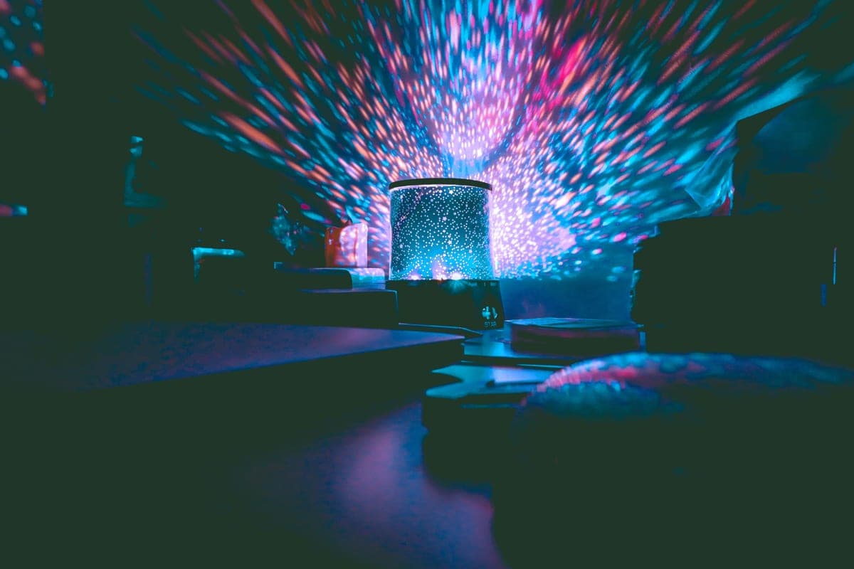 A galaxy projector casting colored light across a dark room