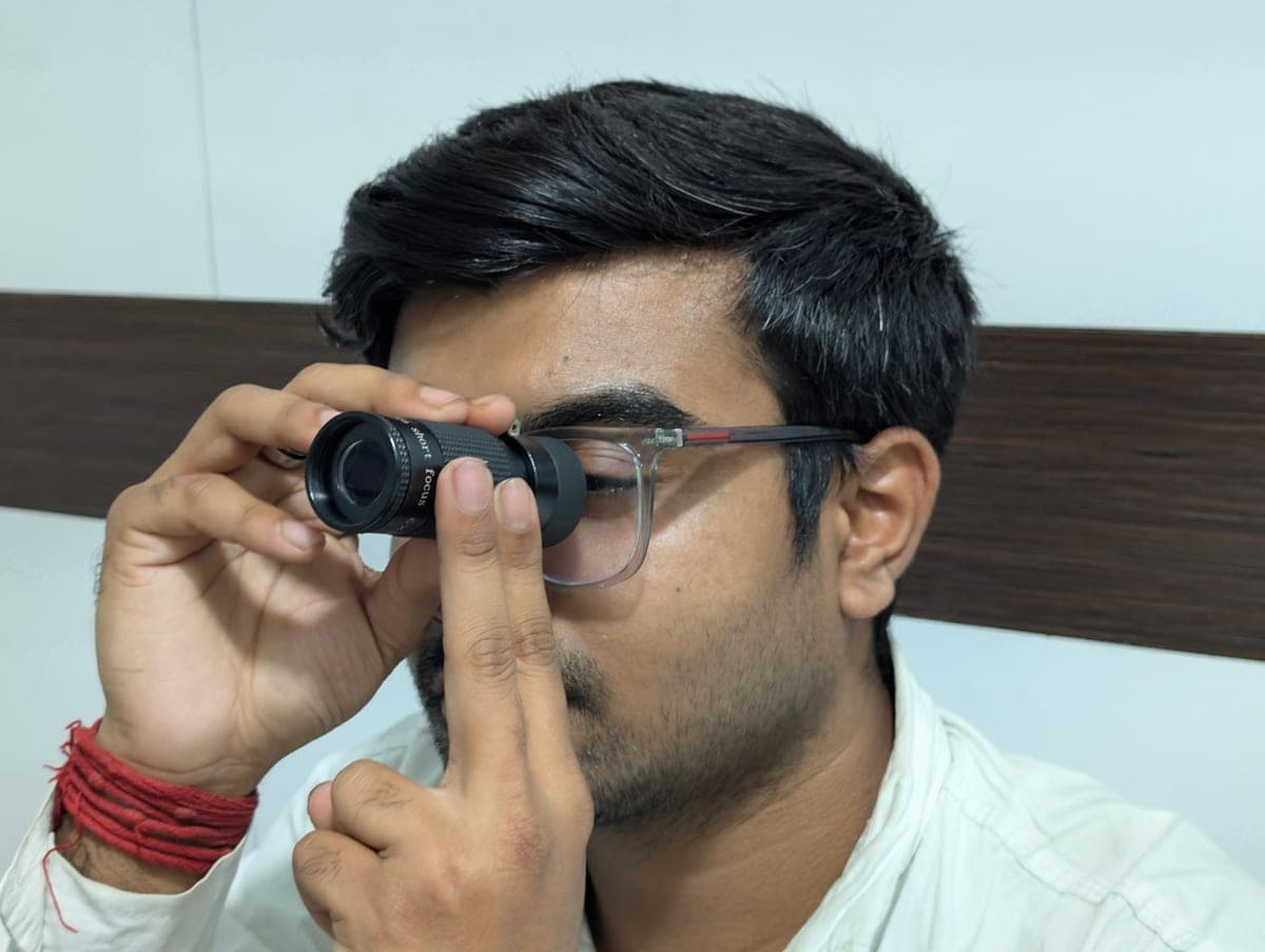 A person looking through a small handheld telescope indoors