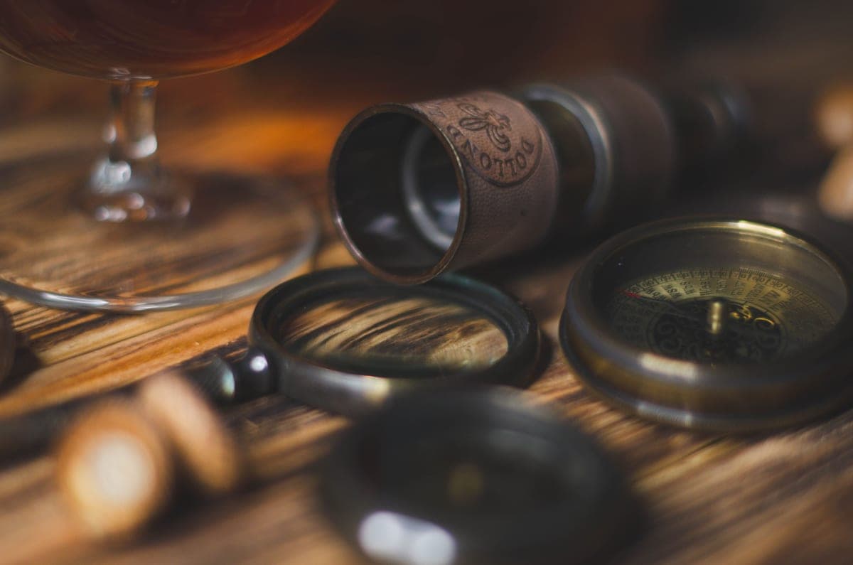 A small telescope and compass resting on a rustic wooden surface