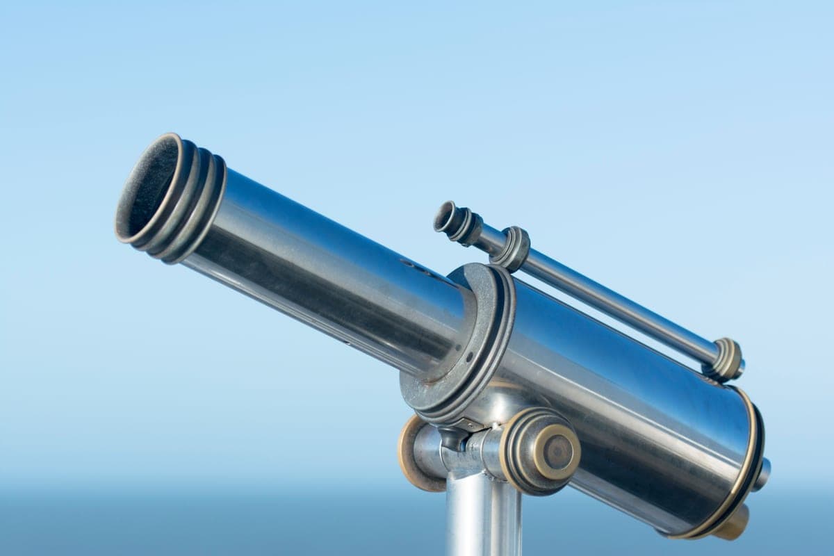 A metal telescope on a mount pointing into a clear sky