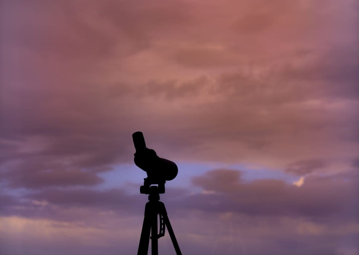 A small refractor telescope on a tripod in a garden