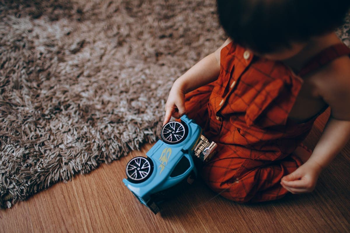 A child holding a small toy telescope indoors