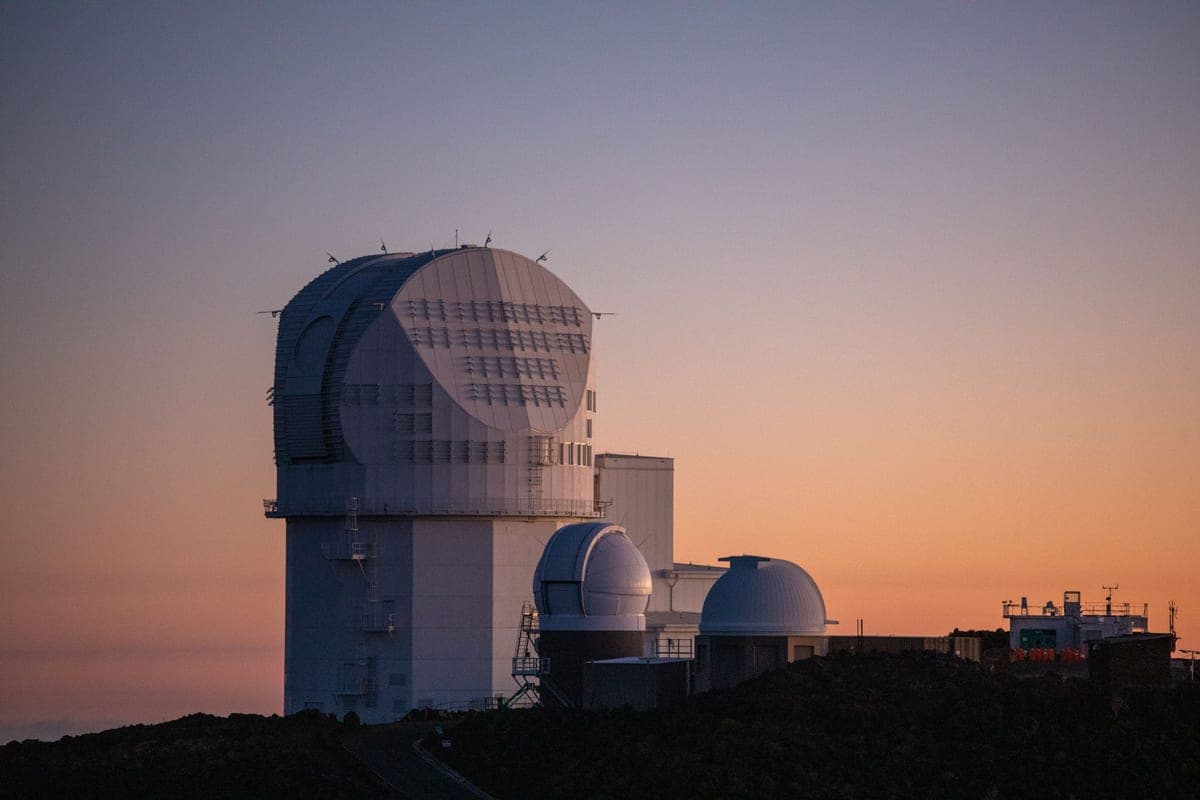 A telescope silhouetted against a deep dusk sky